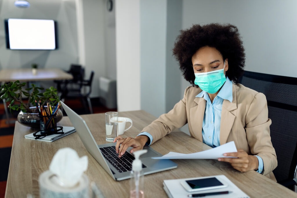 black businesswoman with face mask while going through paperwork office