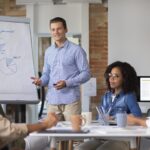 person presenting information meeting white board